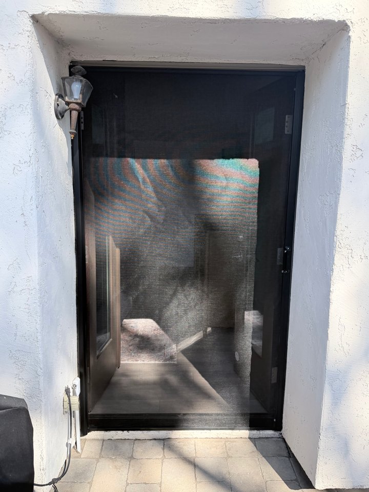 Dark retractable screen fitted within a recessed stucco entryway