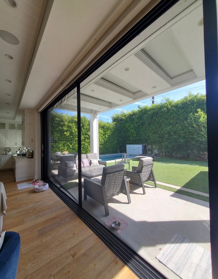 Retractable screen across a wide opening overlooking a patio and garden