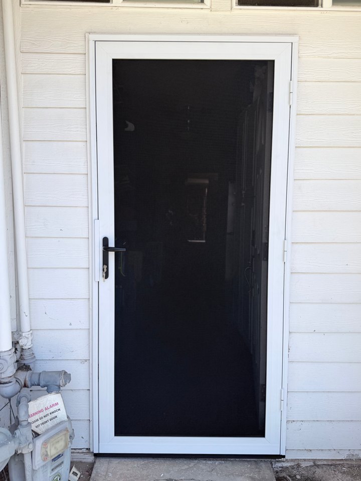 White-framed security screen door fitted to a single entry against white siding
