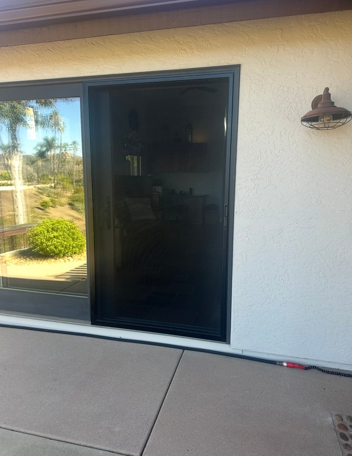 Dark-framed sliding screen door beside a glass patio door and stucco wall