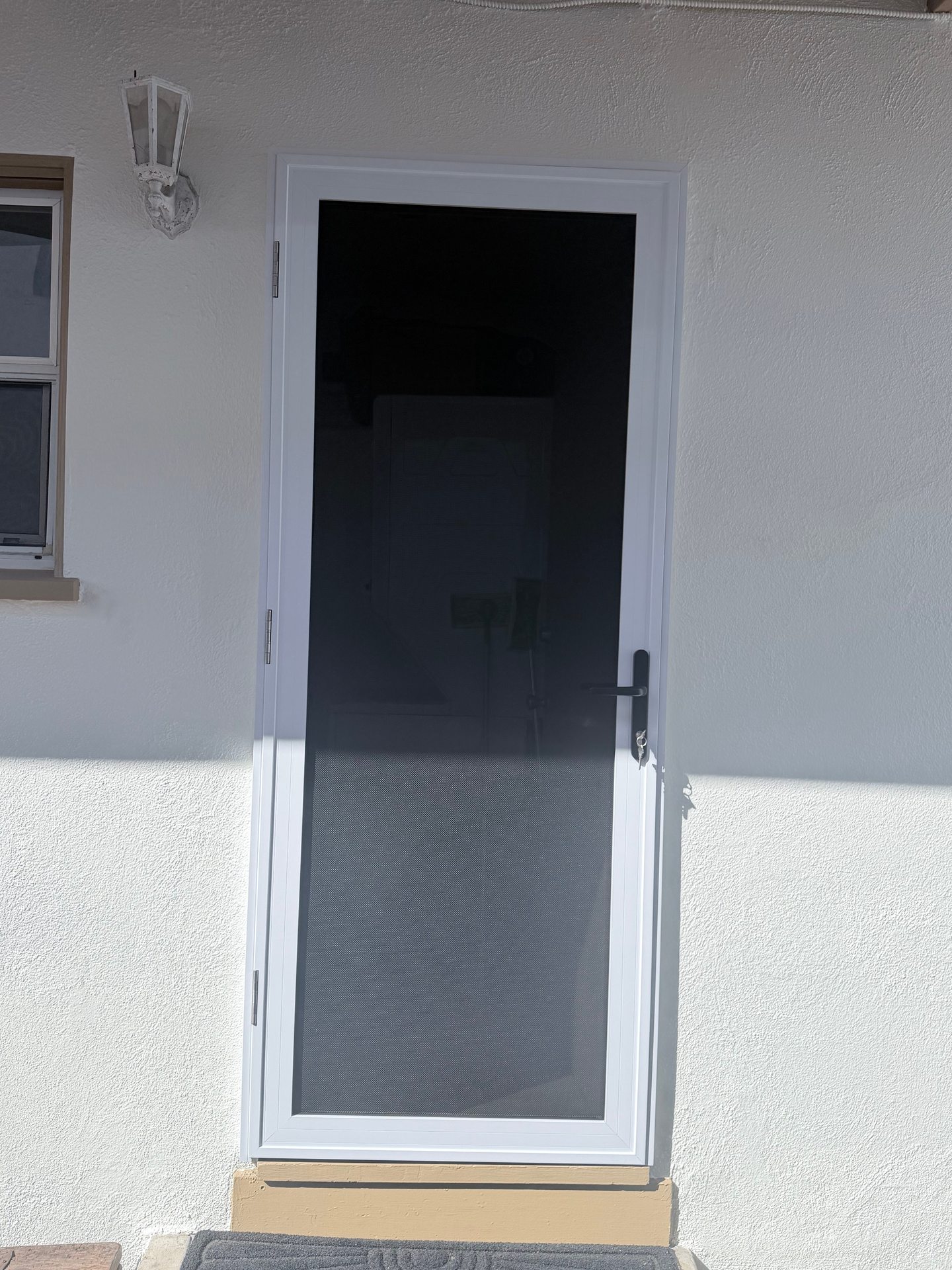 White single-entry security screen door with dark mesh and a black handle